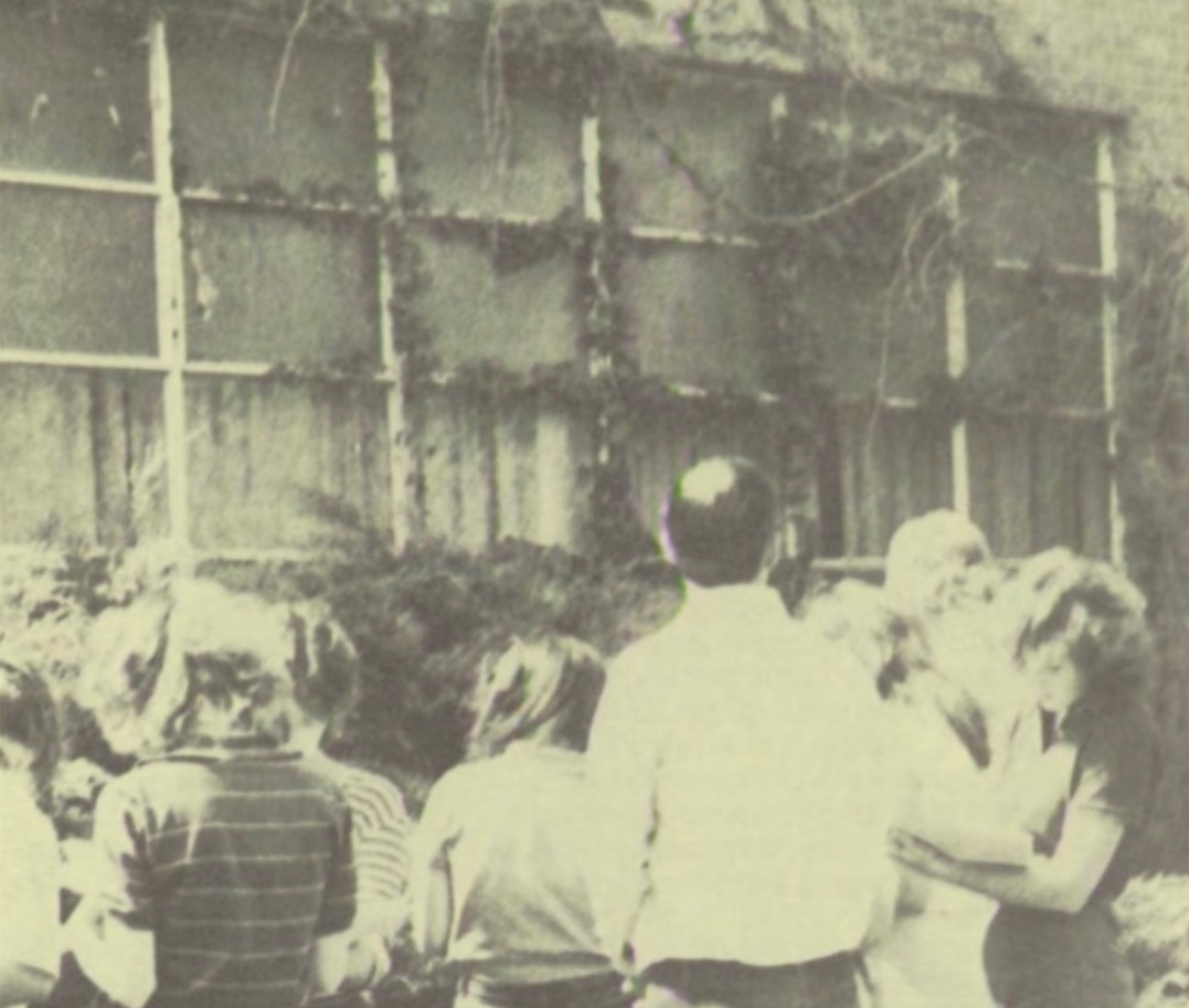 1977 photo of teacher and students inspecting courtyard.